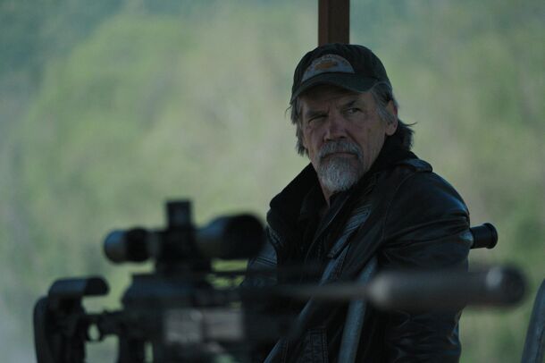 Bangley behind a mounted rifle at the airfield in The Dog Stars