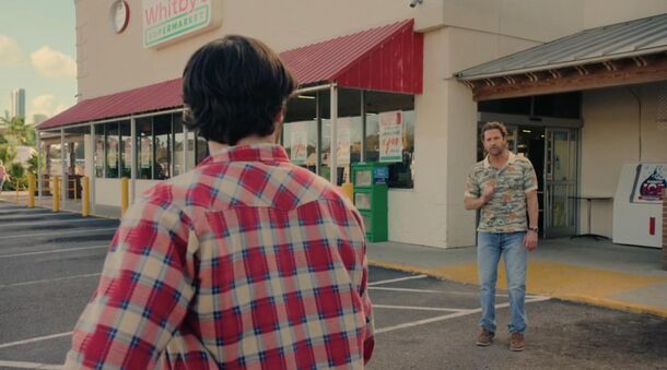 Two men outside a video store in R.J. Decker (2026). In Blame It on the Rain, Ava Kwon's body turns up outside a wedding planned around Hurricane Matilda