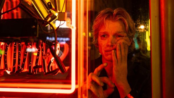 Tom Rhys Harries as Matt Hagen behind a neon sign in Clayface (2026). The R-rated film cost about $40 million, less than a quarter of Supergirl's budget