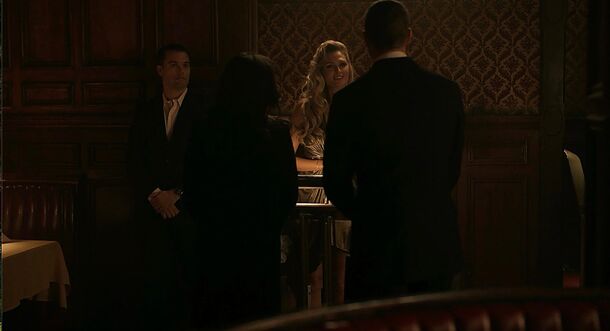 Agents question a group in a dimly lit dining room in NCIS: Origins, the 1991-set prequel