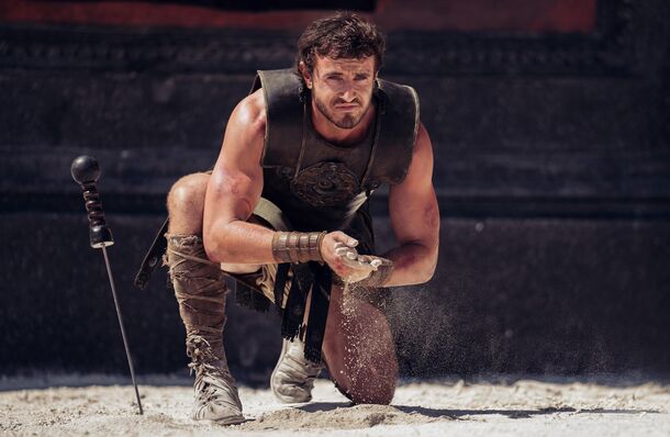 Paul Mescal as Lucius kneeling on the sand in Gladiator II