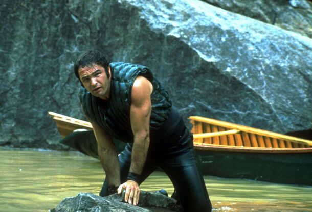 A canoeist dragging his boat onto a rocky riverbank