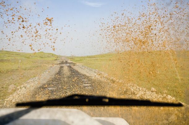 The view through a dusty windshield — the black band at its edge is doing quiet work