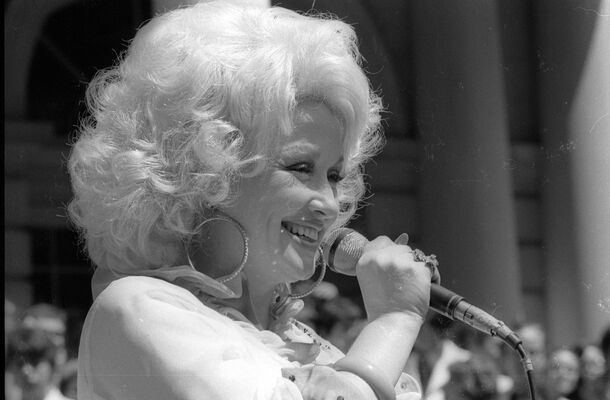 Dolly Parton at the microphone — the same answer for fifty years