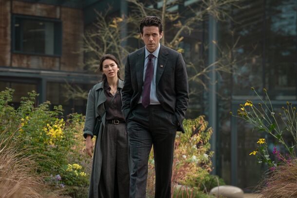 A couple outside a building in daylight in Silo (2023). The season 3 flashbacks follow congressman Daniel Keene and his beloved Helen as the world slides toward catastrophe